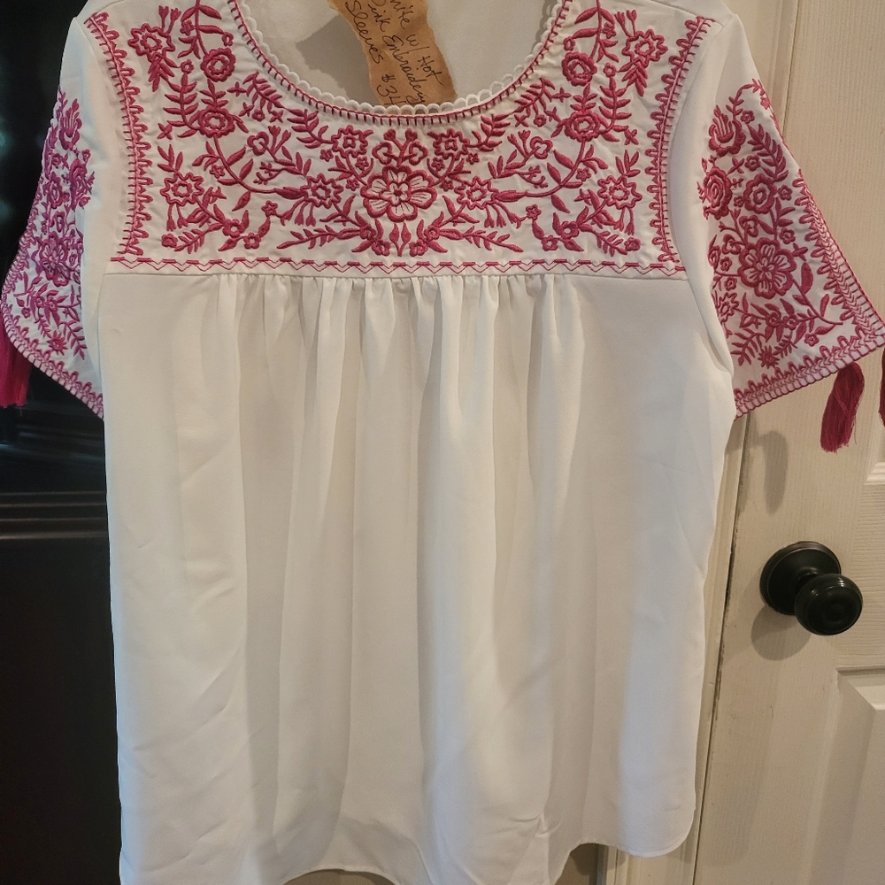 White top with hot pink embroidery and tassels on sleeves